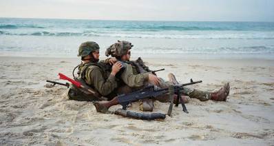 שני חיילים נחים בחוף הים של עזה. מאג מונח לידים
