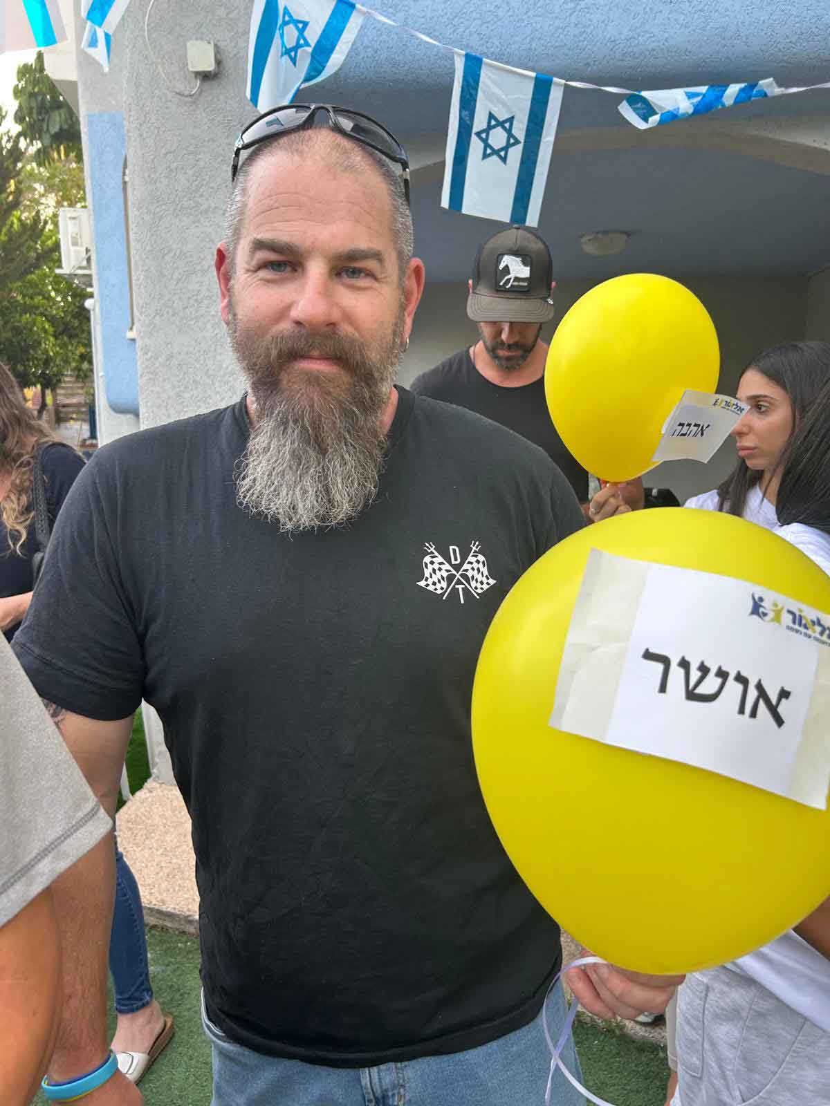 איש אוחז בלון צהוב עם המילה אושר מודבקת עליו