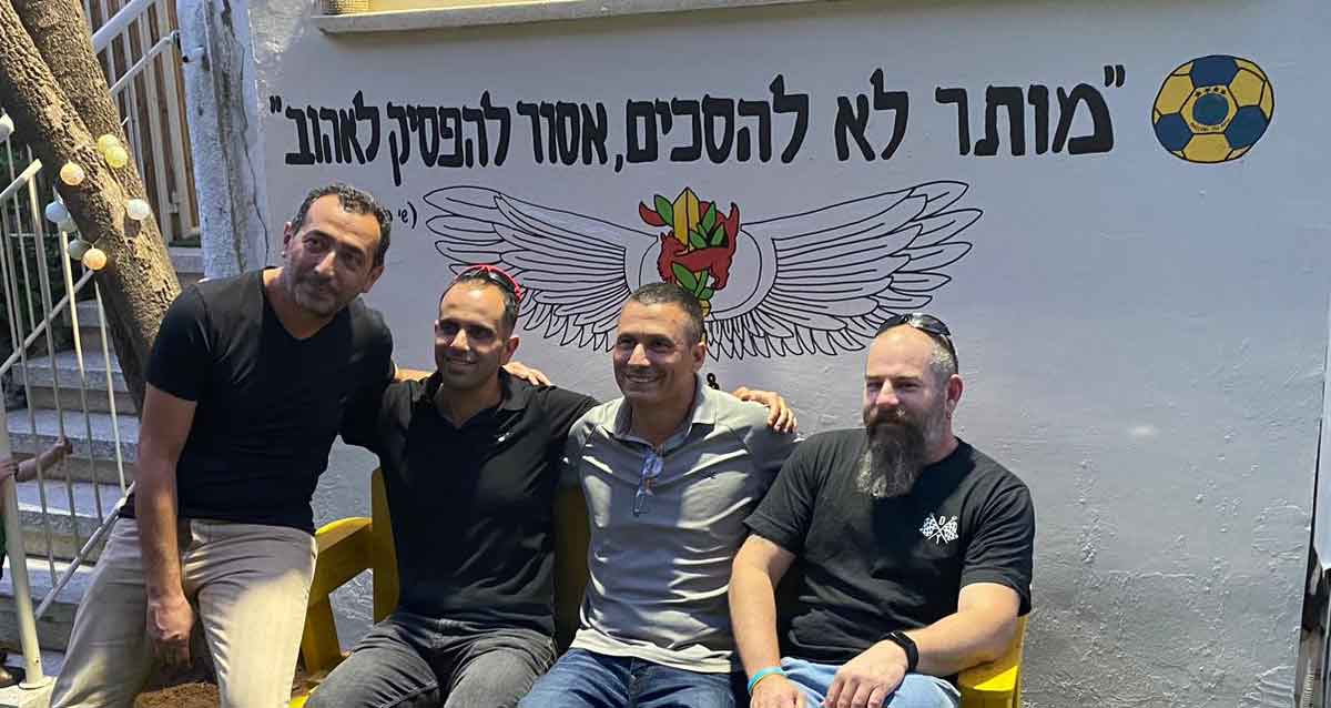 צילום קבוצתי. על קיר מצוייר כדורגל והכיתוב: