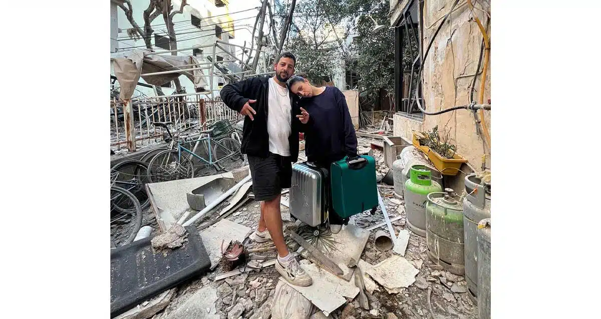 בני זוג שביתם נפגע מטיל בליסטי איראני בלב ת"א במלחמת שאגת הארי. עומדים מחוץ לבית בין שברים עם שני טרולים.